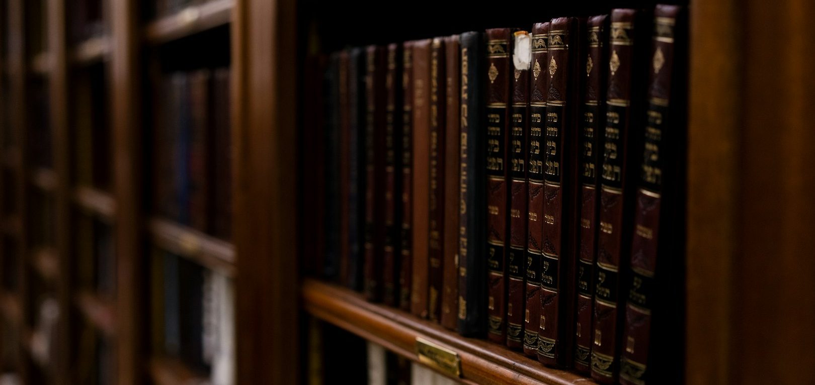 Close-up of a wooden bookshelf filled with antique leather-bound books.