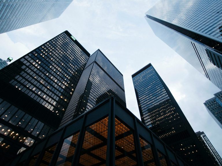 View of skyscrapers from ground level against a cloudy sky.