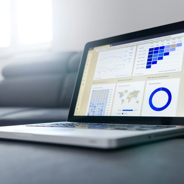 Laptop displaying data visualizations and graphs on a table in a well-lit room.