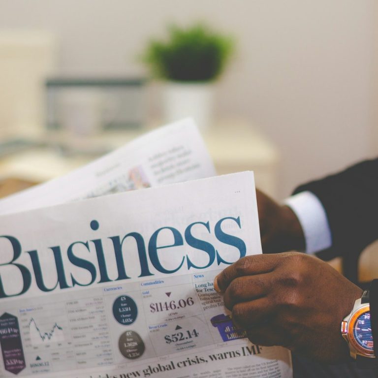 A person holding a newspaper showcasing business news and data.